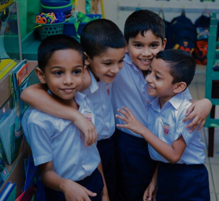 Happy schoolchildren in uniform hugging and smiling in a classroom, reflecting friendship and joy at Kahaduwa National School.