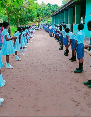 Students in uniform forming parallel lines outside the classroom at Kahaduwa National School, participating in a morning assembly or activity.